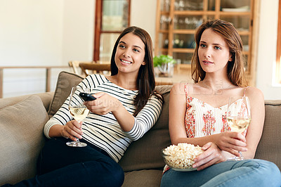 Buy stock photo Shot of two friends watching a movie together on the sofa at home