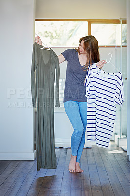 Buy stock photo Shot of a young woman standing in her bedroom choosing outfits