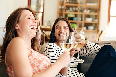 Buy stock photo Shot of two friends talking together and drinking wine while sitting on the sofa at home