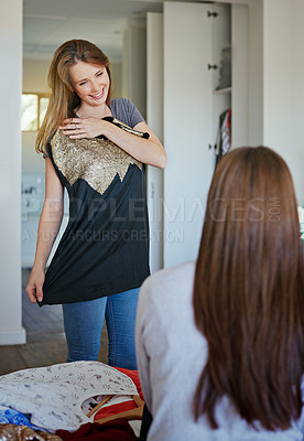Buy stock photo Shot of a young woman helping her friend choose a dress to wear while standing in a bedroom