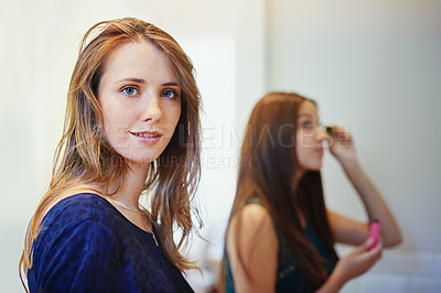 Buy stock photo Shot of two young woman putting on makeup in a bathroom
