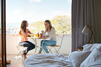 Buy stock photo Shot of two friends eating breakfast together on a balcony