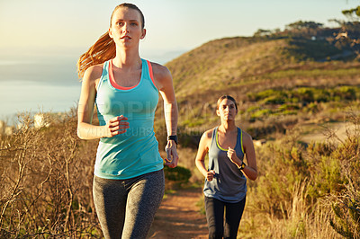 Buy stock photo Shot of two young woman out for a cross country run