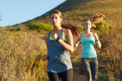 Buy stock photo Shot of two young woman out for a cross country run