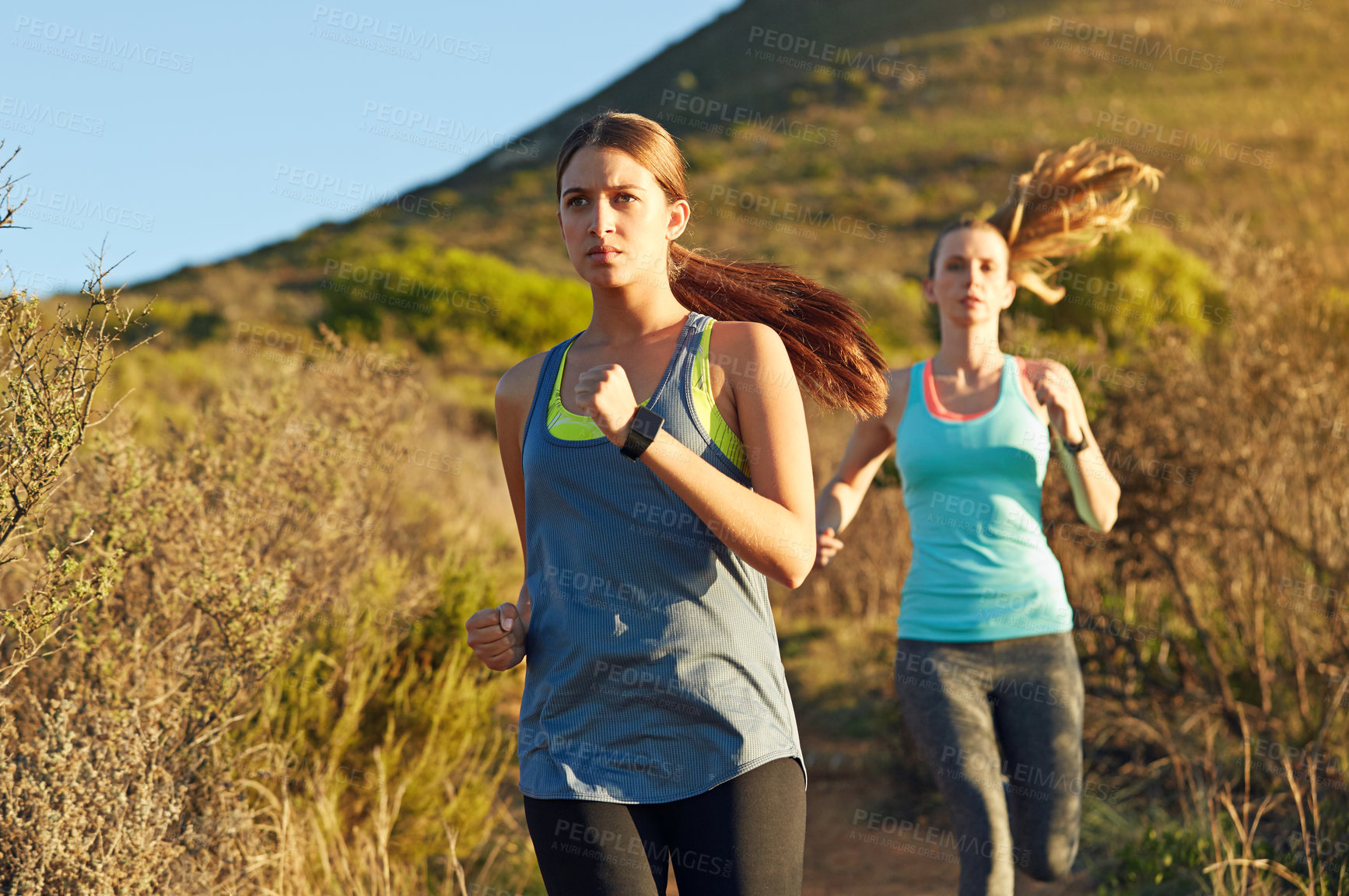 Buy stock photo Shot of two young woman out for a cross country run