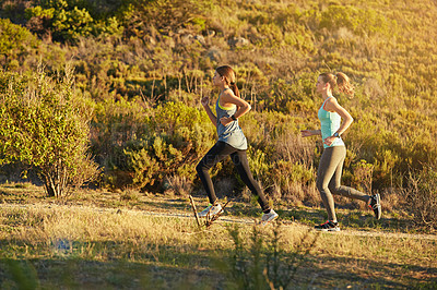 Buy stock photo Shot of two young woman out for a cross country run