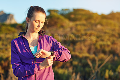 Buy stock photo Shot of a young woman checking her time while out for a trail run