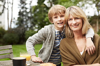 Buy stock photo Portrait of a grandmother and her grandson sitting at a table in her yard