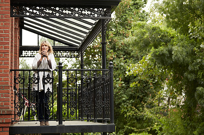 Buy stock photo Portrait of a mature woman leaning against the railing of her front porch drinking a coffee