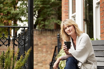 Buy stock photo Shot of a mature woman sitting on her front porch drinking a cup of coffee