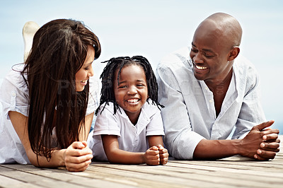 Buy stock photo Portrait of a young family lying on a boardwalk outside