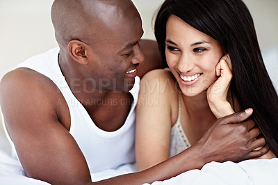 Buy stock photo Shot of an affectionate young couple lying in bed together