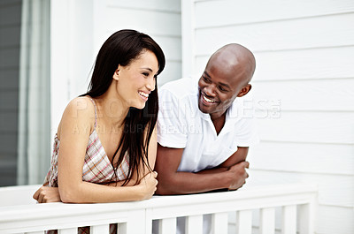 Buy stock photo Shot of a young couple leaning on the railing of their balcony