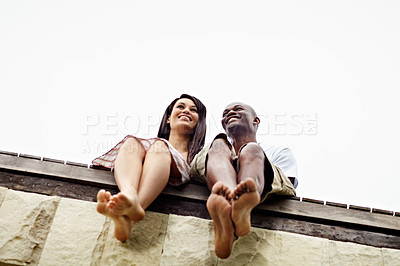 Buy stock photo Low angle shot of a young couple sitting together on the edge of a boardwalk
