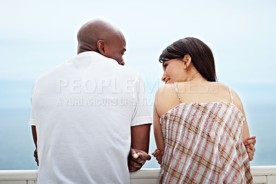 Buy stock photo Rearview shot of a young couple leaning on a railing by the ocean