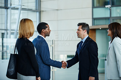 Buy stock photo Shot of businesspeople shaking hands together in the lobby of an office building