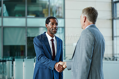 Buy stock photo Shot of two businessmen shaking hands together in the lobby of an office building