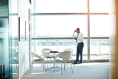 Buy stock photo Shot of a businessman standing in an office reading a text message