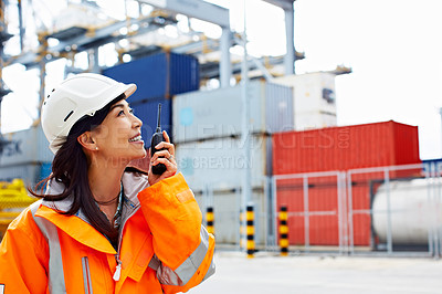 Buy stock photo Shot of a woman in workwear talking on a walkietalkie while standing on a commercial dock