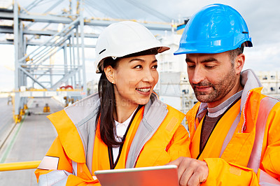 Buy stock photo Shot of two workers talking together over a digital tablet while standing on a commercial dock