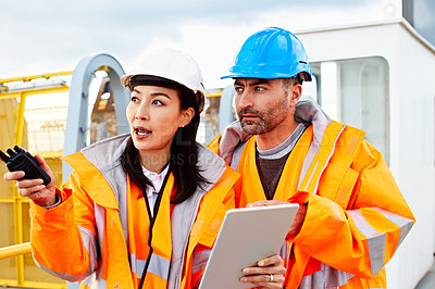Buy stock photo Shot of two workers talking together over a digital tablet while standing on a commercial dock