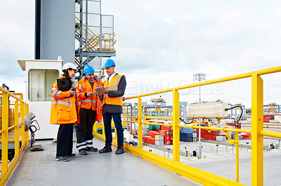 Buy stock photo Shot of workers talking over a digital tablet while standing on a large commercial dock