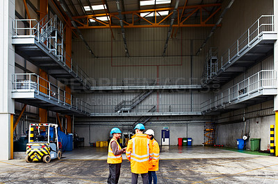 Buy stock photo Shot of three dock workers standing in front of a large commercial warehouse