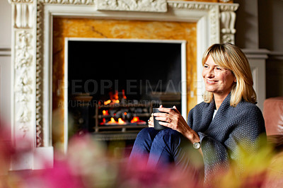 Buy stock photo Shot of a mature woman relaxing on her living room sofa with a fire glowing in the background