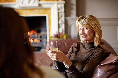 Buy stock photo Shot of a woman drinking wine while talking with her daughter on the living room sofa