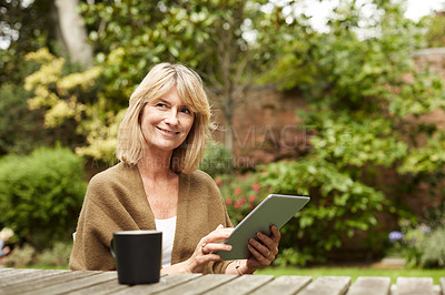 Buy stock photo Portrait of a mature woman sitting in her yard drinking tea and using a digital tablet