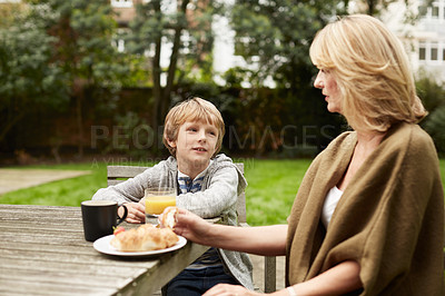 Buy stock photo Shot of a grandmother and her grandson have lunch at a table in her yard