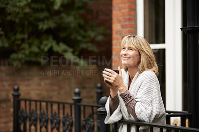 Buy stock photo Shot of a mature woman leaning against the railing of her front porch drinking a coffee