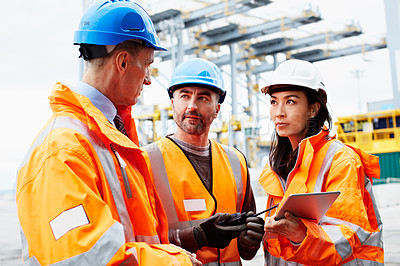 Buy stock photo Shot of three workers talking together over a digital tablet while standing on a commercial dock