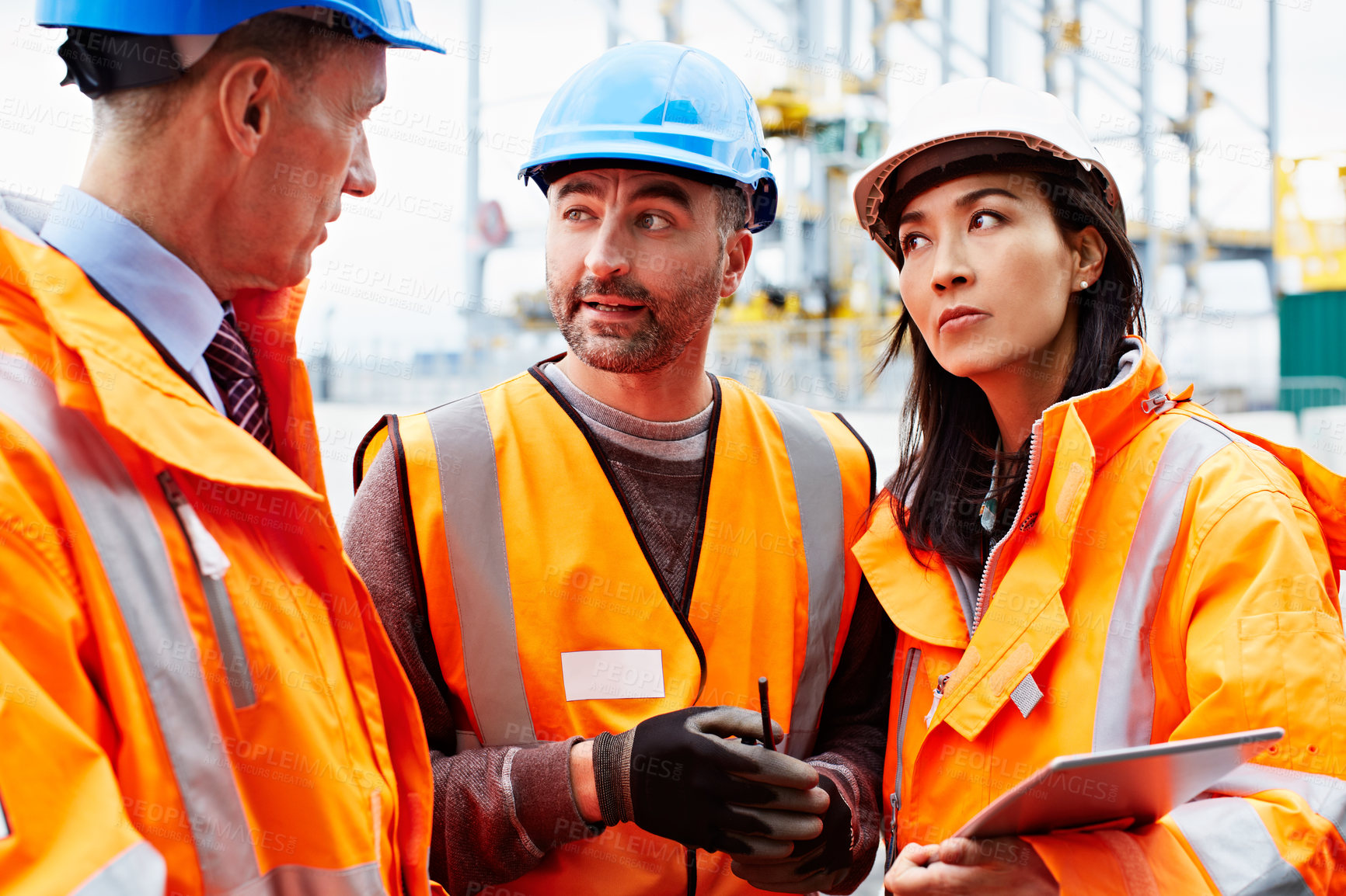Buy stock photo Shot of three workers talking together over a digital tablet while standing on a commercial dock
