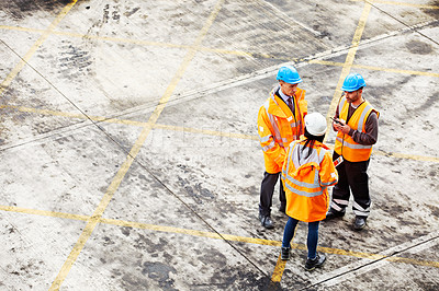 Buy stock photo Shot of three workers talking together while standing on a commercial dock