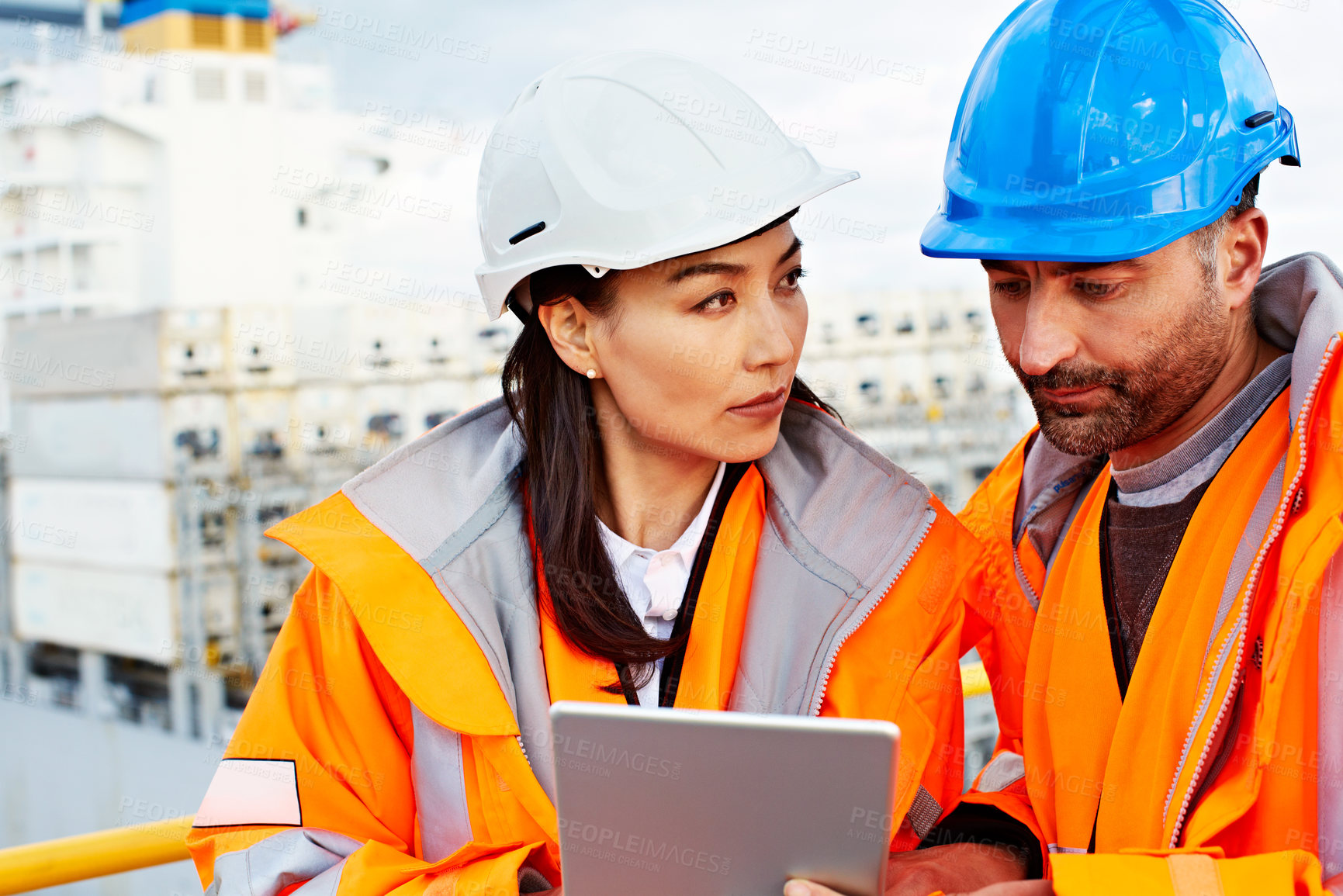 Buy stock photo Shot of two people talking over a digital tablet while standing on a large commercial dock