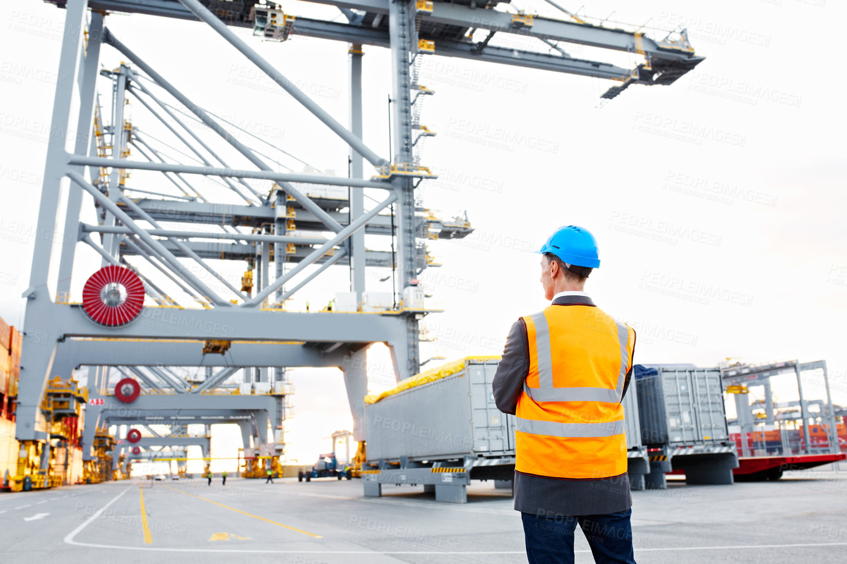 Buy stock photo Rearview shot of a man in workwear standing on a large commercial dock