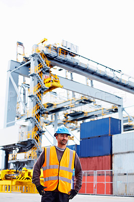 Buy stock photo Shot of a young man in workwear standing outside on a large commercial dock