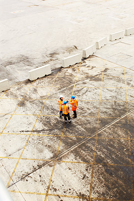 Buy stock photo High angle shot of three workers talking together while standing on a commercial dock
