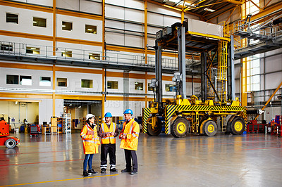 Buy stock photo Shot of three workers standing in a large commercial warehouse