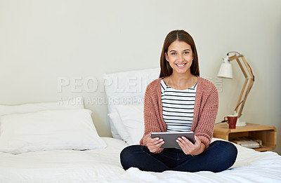Buy stock photo Portrait of a young woman sitting on her bed using a digital tablet