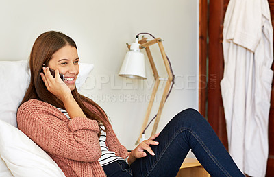 Buy stock photo Shot of a young woman sitting on her bed talking on a cellphone