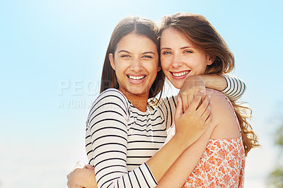 Buy stock photo Portrait of two young friends hugging while enjoying a day outside together