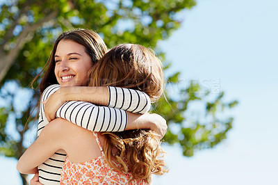 Buy stock photo Shot of two young friends hugging while enjoying a day outside together