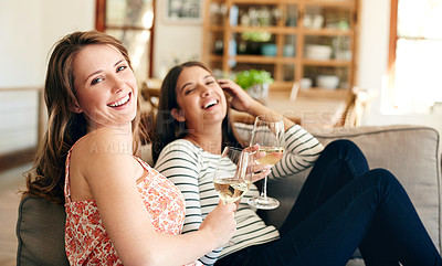Buy stock photo Portrait of two friends talking together and drinking wine while sitting on the sofa at home