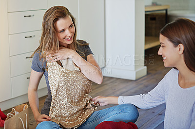 Buy stock photo Shot of two friends sititng in the bedroom looking through shopping bags of clothiing