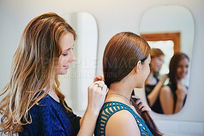 Buy stock photo Shot of a young woman helping her friend put on a necklace