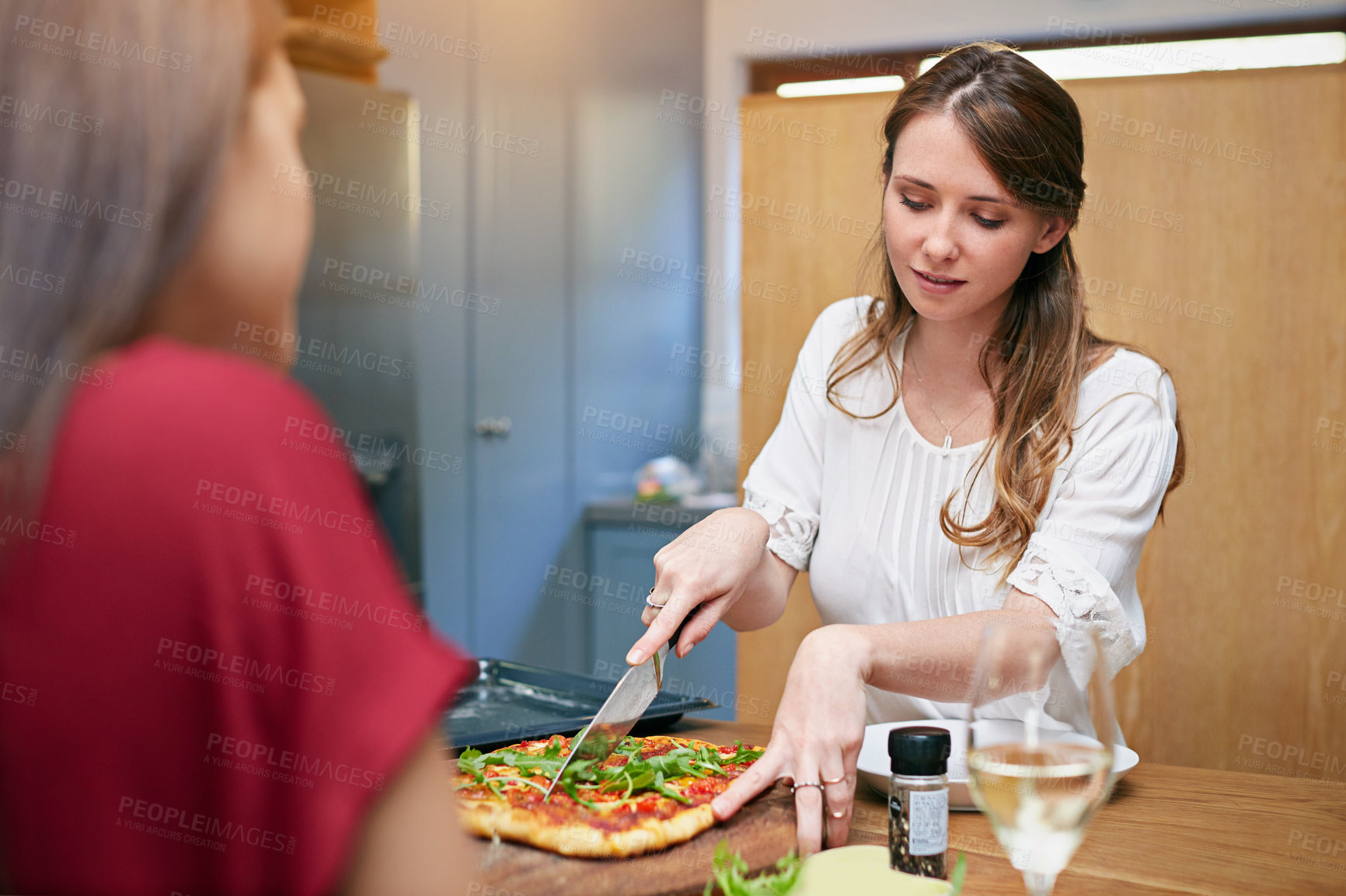 Buy stock photo Women, serving and pizza with lunch, relax and together with chat for bonding in home kitchen. People, friends and gossip with wine, snack and conversation with food for support or relationship