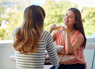 Buy stock photo Shot of two friends eating breakfast together on a balcony