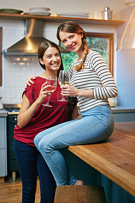 Buy stock photo Portrait of two friends drinking wine together in the kitchen